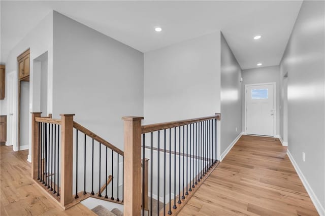 hallway featuring baseboards, recessed lighting, an upstairs landing, and light wood-style floors