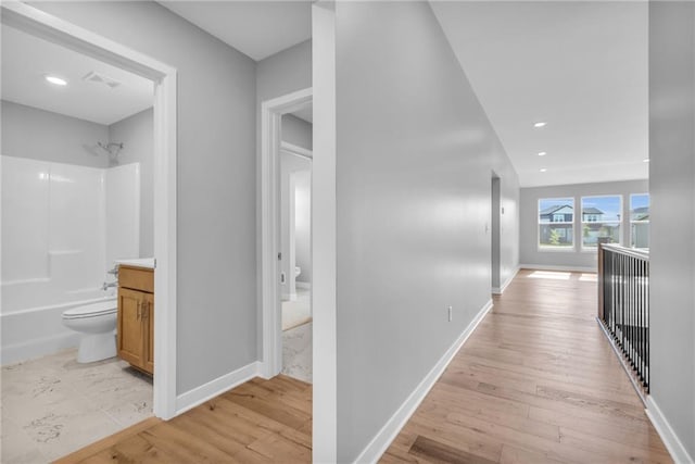 hallway featuring recessed lighting, baseboards, and light wood finished floors