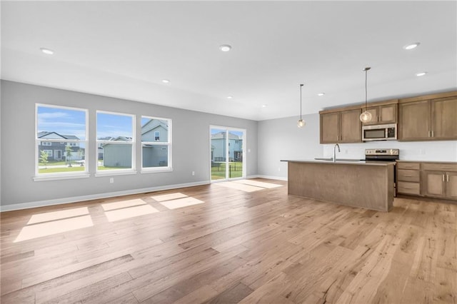 kitchen with open floor plan, appliances with stainless steel finishes, light wood finished floors, and recessed lighting