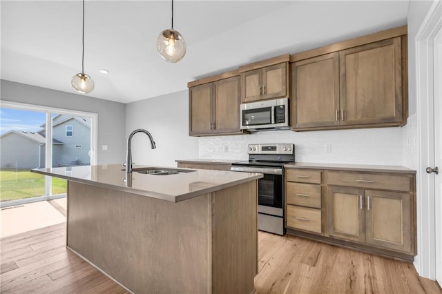 kitchen featuring stainless steel appliances, light wood-type flooring, a sink, and tasteful backsplash