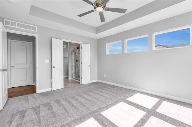 unfurnished bedroom featuring a ceiling fan, visible vents, baseboards, carpet, and a raised ceiling