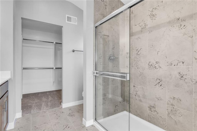 full bath featuring a walk in closet, visible vents, a shower stall, vanity, and baseboards