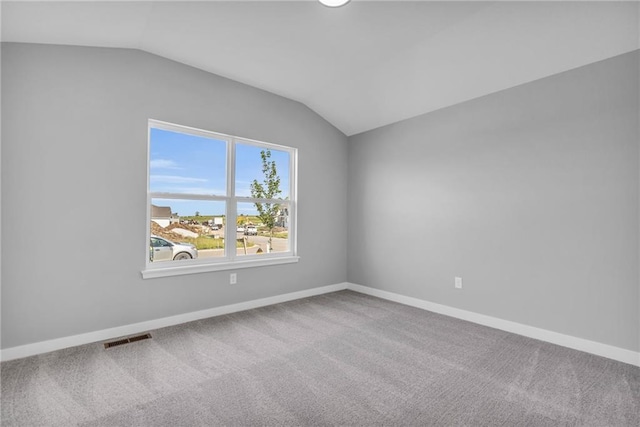 carpeted spare room with lofted ceiling, baseboards, and visible vents