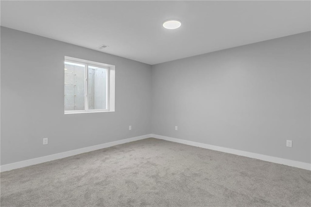 spare room featuring carpet floors, visible vents, and baseboards