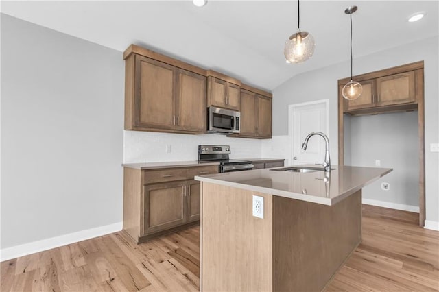 17756 Houston St, Gardner, KS 66030 - kitchen with stainless steel appliances, light wood-type flooring, vaulted ceiling, decorative light fixtures, and an island with sink