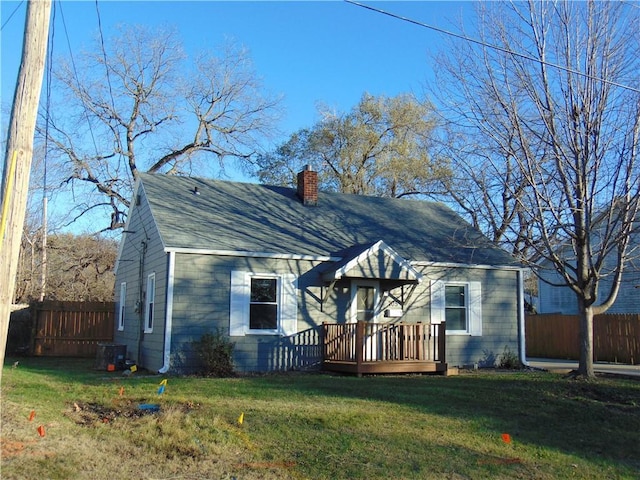 view of front of home with a front yard, central AC, and a wooden deck