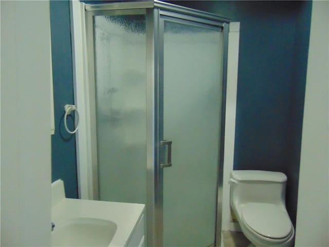 bathroom featuring vanity, an enclosed shower, and toilet