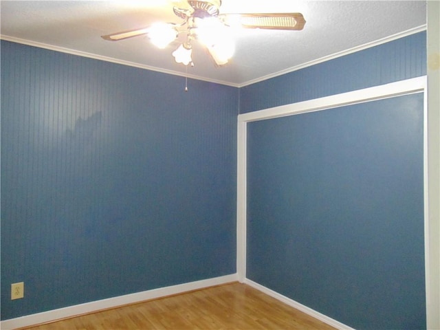 empty room featuring ceiling fan, crown molding, and wood-type flooring