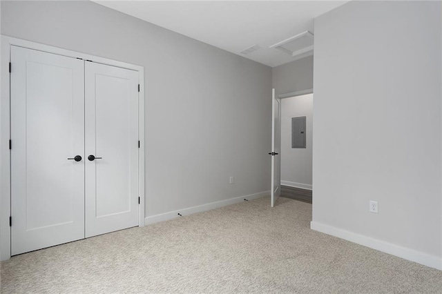 unfurnished bedroom featuring light carpet, attic access, electric panel, baseboards, and visible vents