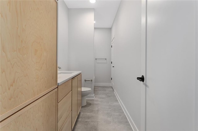 bathroom with toilet, vanity, and baseboards