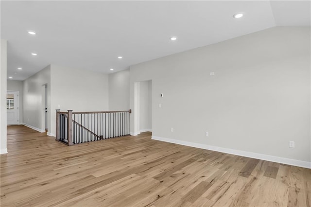 unfurnished room featuring lofted ceiling and light hardwood / wood-style floors