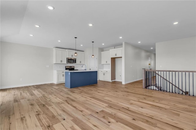 kitchen featuring stainless steel appliances, hanging light fixtures, a center island with sink, and white cabinets