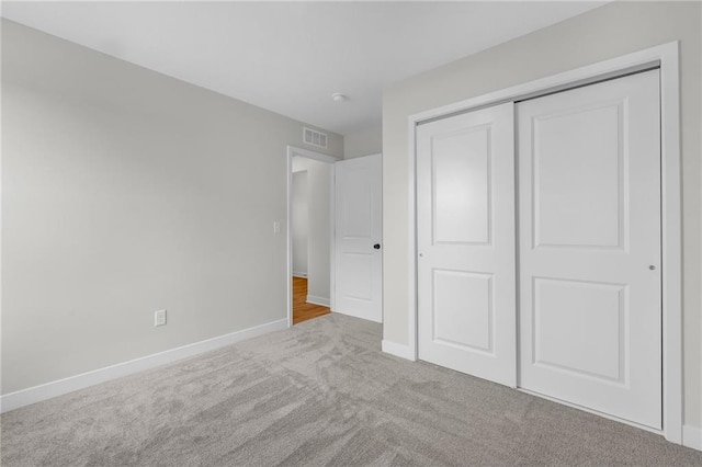 unfurnished bedroom featuring light carpet and a closet