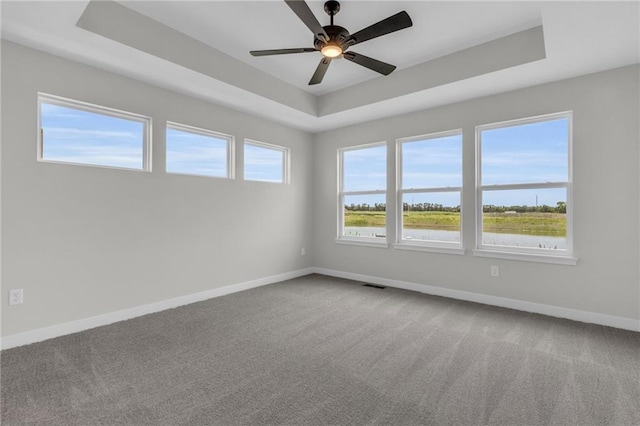 carpeted spare room with a tray ceiling and ceiling fan