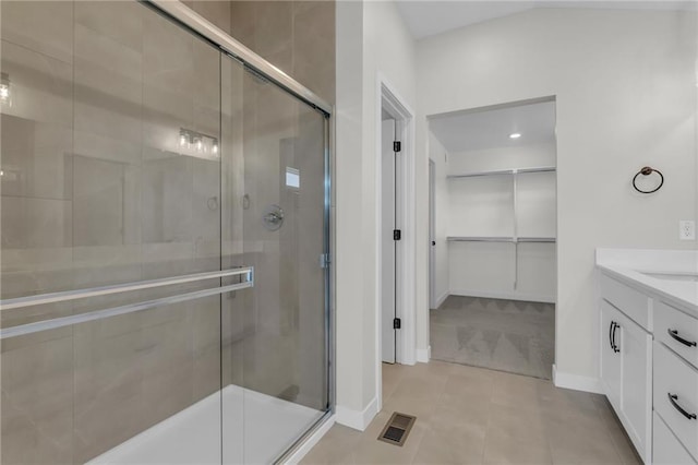 bathroom with a stall shower, a spacious closet, visible vents, and vanity