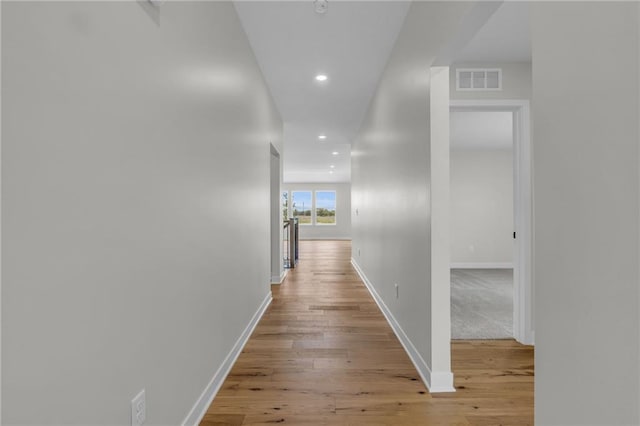 corridor with visible vents, light wood-style flooring, and baseboards