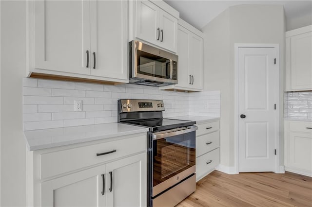 kitchen featuring white cabinets, decorative backsplash, light wood-style flooring, stainless steel appliances, and light countertops