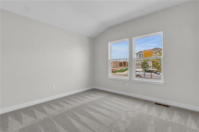 carpeted empty room with lofted ceiling, visible vents, and baseboards