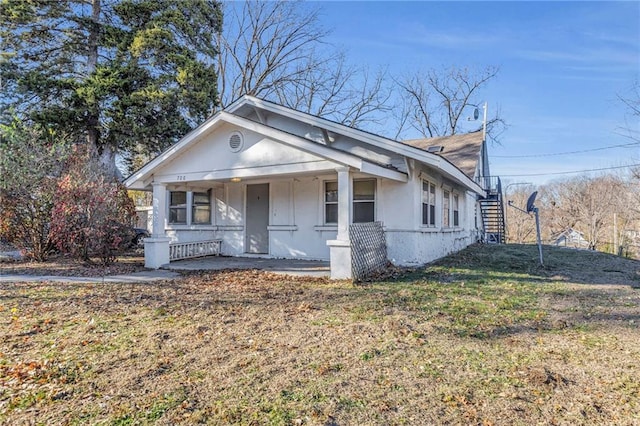 bungalow-style house featuring covered porch and a front lawn