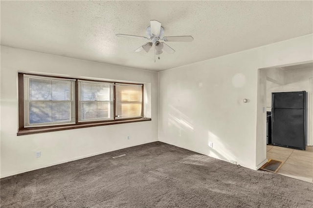 carpeted spare room featuring ceiling fan and a textured ceiling