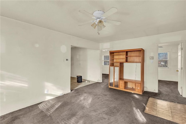 unfurnished living room featuring dark colored carpet and ceiling fan