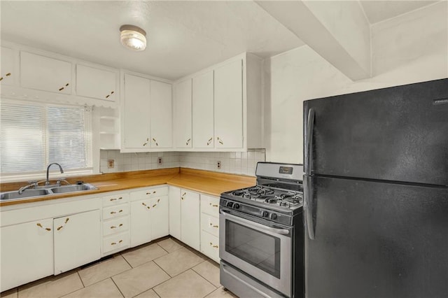 kitchen with sink, stainless steel range with gas cooktop, black fridge, backsplash, and white cabinets