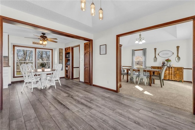 dining space featuring wood-type flooring and ceiling fan with notable chandelier