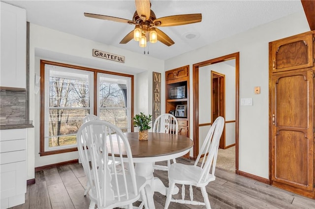 dining area with light wood-type flooring and ceiling fan