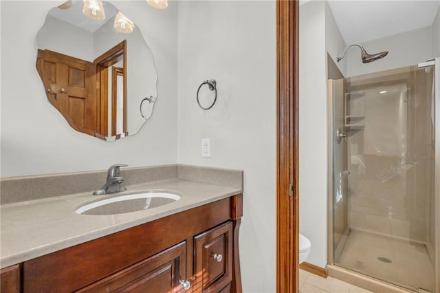 bathroom featuring tile patterned floors, vanity, a shower with shower door, and toilet