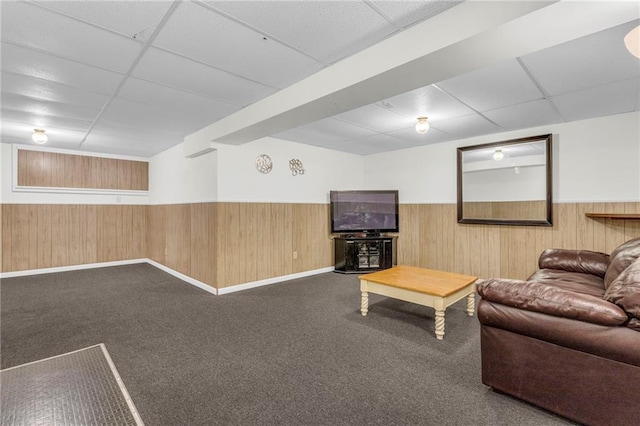 unfurnished living room with carpet flooring, a paneled ceiling, and wooden walls