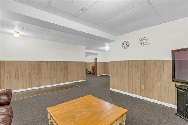 carpeted living room featuring a paneled ceiling and wooden walls