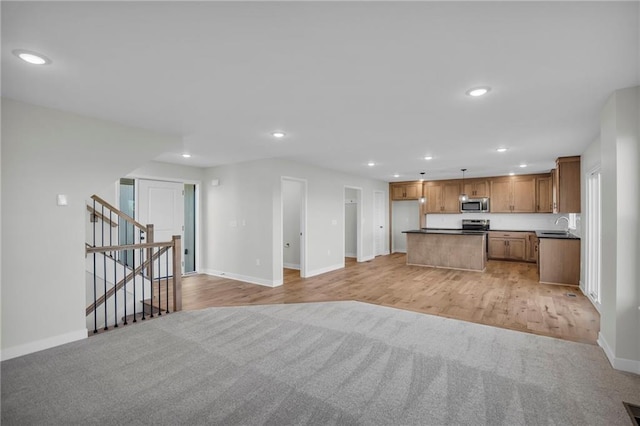 kitchen with stainless steel appliances, hanging light fixtures, a center island, and light carpet