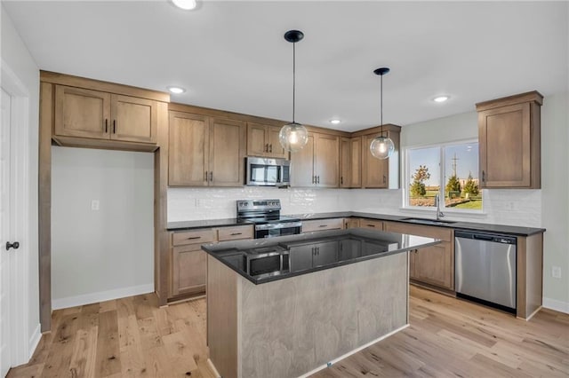 kitchen with appliances with stainless steel finishes, pendant lighting, sink, a center island, and light hardwood / wood-style flooring