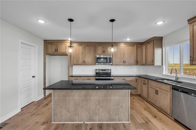 kitchen with a kitchen island, appliances with stainless steel finishes, sink, backsplash, and hanging light fixtures