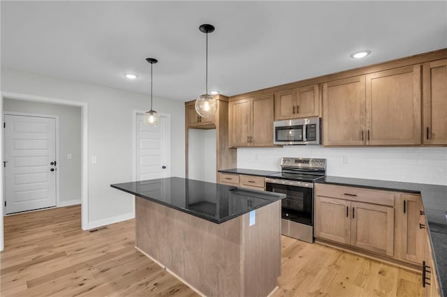 kitchen featuring a kitchen island, appliances with stainless steel finishes, pendant lighting, decorative backsplash, and light hardwood / wood-style floors