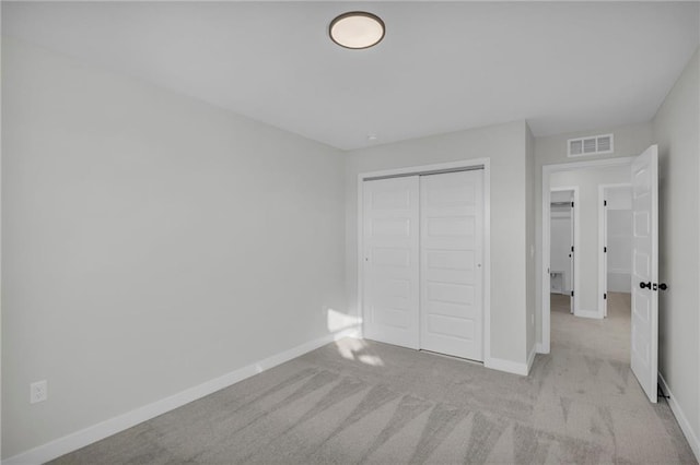 unfurnished bedroom featuring light carpet and a closet