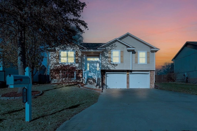 bi-level home featuring a garage and a lawn