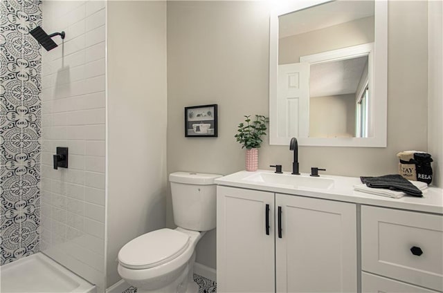 bathroom with vanity, toilet, and tiled shower