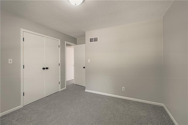 unfurnished bedroom with carpet, a textured ceiling, and a closet