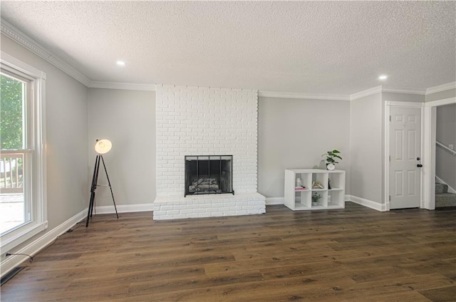 unfurnished living room with a fireplace, a textured ceiling, dark hardwood / wood-style flooring, and ornamental molding