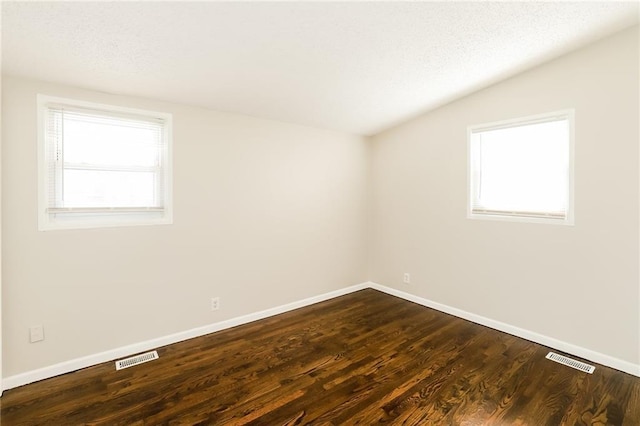 empty room with dark hardwood / wood-style floors, a healthy amount of sunlight, and lofted ceiling