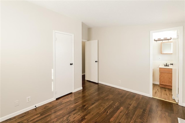 unfurnished bedroom featuring connected bathroom, dark hardwood / wood-style floors, and lofted ceiling