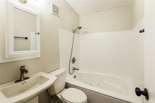 full bathroom featuring tiled shower / bath combo, toilet, and sink