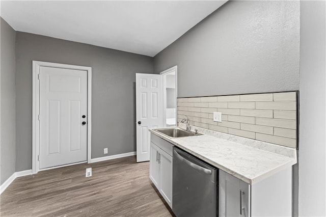 kitchen with white cabinetry, sink, tasteful backsplash, stainless steel dishwasher, and hardwood / wood-style flooring