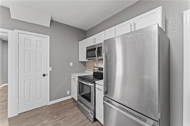 kitchen with white cabinets, wood-type flooring, stainless steel appliances, and tasteful backsplash