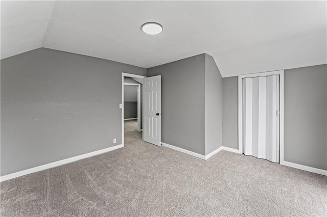 additional living space featuring light colored carpet and lofted ceiling