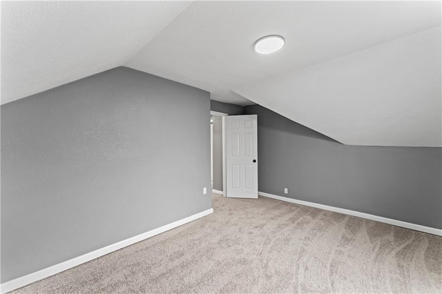 additional living space with light colored carpet and vaulted ceiling