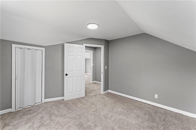 additional living space featuring light colored carpet and lofted ceiling