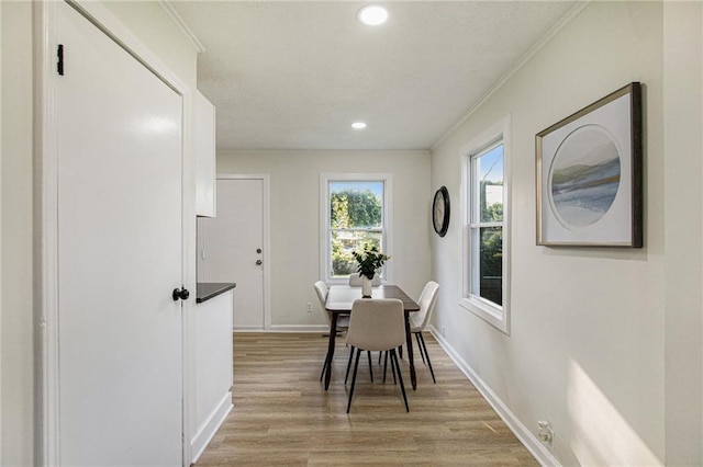 dining space featuring light hardwood / wood-style floors and crown molding