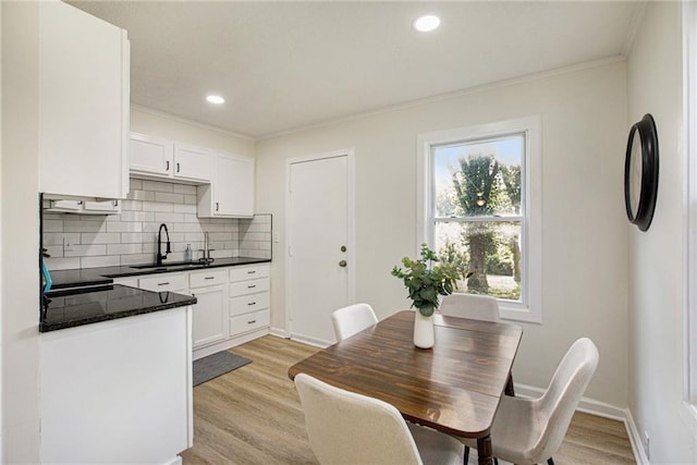 dining space featuring light hardwood / wood-style floors, crown molding, and sink